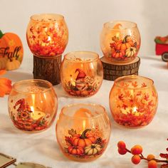 there are many pumpkins and candles in glass bowls on the table with autumn decorations