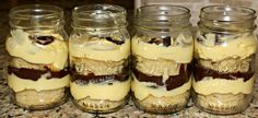 four jars filled with desserts sitting on top of a counter