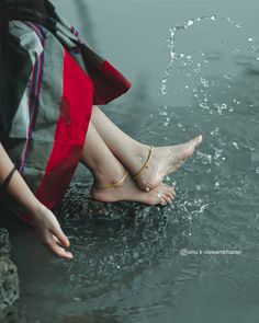 a woman is sitting in the water with her feet up