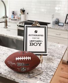 a football sitting on top of a kitchen counter next to a clipboard with autographs for the boys written on it