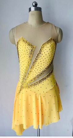 a yellow dress with gold sequins on the front and back, sitting on a mannequin