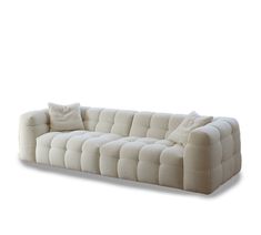 a white couch sitting on top of a white floor next to a pillow and pillows