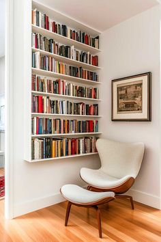 a white chair sitting in front of a bookshelf filled with lots of books