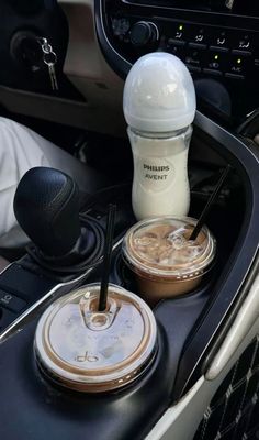 there are two drinks in the cup holder on this car dash board, and one is filled with coffee