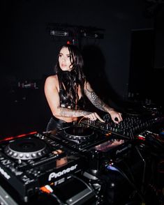 a woman with long hair playing music on a dj's deck