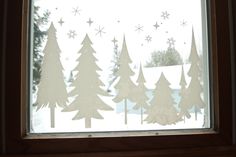 the window is decorated with paper trees and snowflakes