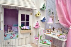 a doll house with pink curtains and furniture in it's room, including a bed