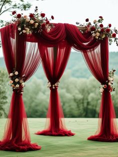 an outdoor wedding setup with red drapes and flowers