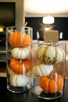 two glass vases filled with pumpkins on top of a table