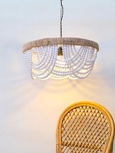 a chandelier hanging from the ceiling next to a wicker chair and table