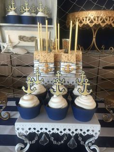 some cupcakes are sitting on top of blue and white striped cake plates with gold decorations