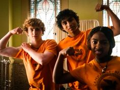 two young men flexing their muscles in front of stained glass windows at the same time