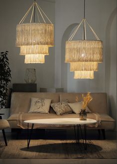 two chandeliers hanging from the ceiling above a couch with pillows and pillows on it