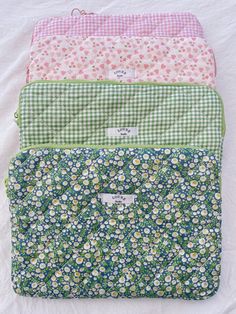 four flowered bags are lined up on top of each other, one is green and the other is pink