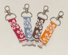 four keychains with different designs on them are shown in the shape of hearts