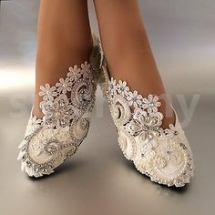 a woman's feet wearing white shoes with lace and beads on the bottom part