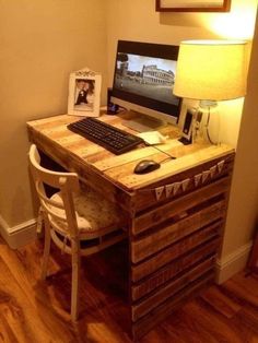 a desk with a computer on top of it next to a lamp and pictures hanging on the wall