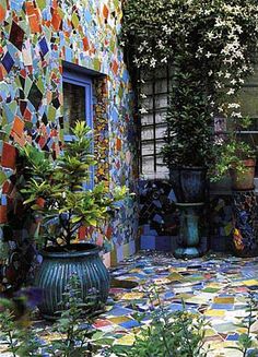 an outdoor area with potted plants and colorful tiles on the wall