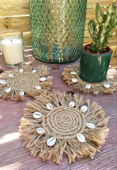 three coasters with shells are sitting on a table next to a potted plant