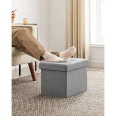 a person sitting on a chair with their feet up in a footstool and reading a book