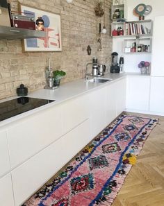 a kitchen area with a rug on the floor and white cabinets in front of it