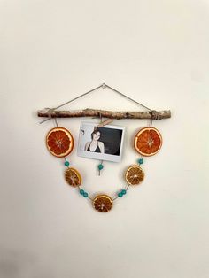 an orange slice hanging on a wall with a photo and beaded necklace attached to it