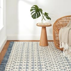 a living room with a chair, rug and potted plant on the side table