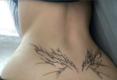 a woman's lower back tattoo with branches and stars on her left side ribcage