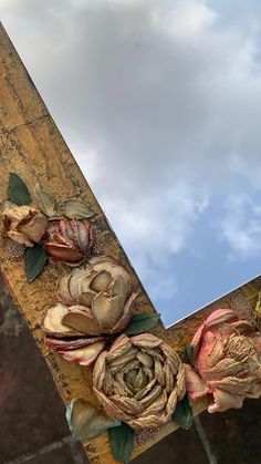 two flowers are placed on the edge of a piece of wood with sky in the background