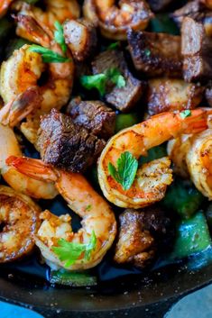 a skillet filled with shrimp, steak and veggies