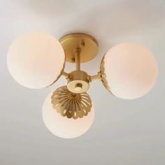 three light fixture with white glass shades on the ceiling in a living room or bedroom