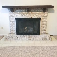 an empty fireplace in a living room with white walls and carpet on the floor,