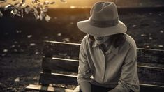 a woman sitting on a bench wearing a hat