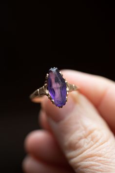 Very pretty handmade 10k gold ring with a purple synthetic glass stone, that is to look like an amethyst. The gem has some wear to it on the surface, but no chips. The style looks like it might have had an alaskan black diamond, and replaced with the purple stone. Very unique looking  ring! size 8.25 2.5 grams stone size 20mm x 7mm 👋🏽 We charge an additional $50 if you are interested in having this ring resized. There is a 2 week (or less) turn around time. Please go to this listing https://ww Heirloom Purple Jewelry With Bezel Setting, Heirloom Purple Birthstone Jewelry, Purple Marquise Jewelry For Formal Occasions, Heirloom Oval Amethyst Jewelry, Heirloom Oval Purple Jewelry, Vintage Marquise Gemstone Jewelry, Fine Jewelry Amethyst Marquise Ring, Oval Amethyst Jewelry Collectible, Fine Jewelry Marquise Amethyst Ring