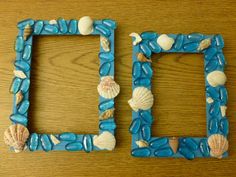 two blue frames with shells and seashells on them sitting on a wooden table