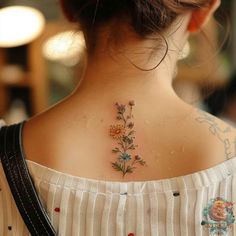 a woman with a flower tattoo on her upper back neck and behind the neck is a white striped shirt