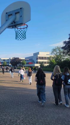 many people are walking around in the park with a basketball hoop hanging from it's side