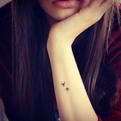 a woman with a small bird tattoo on her left wrist and right hand behind her head