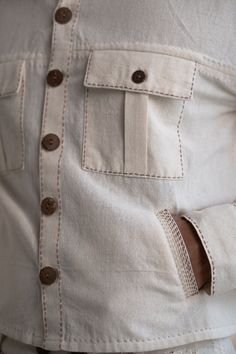 This Dawning Shirt Jacket and Tapered Pants Set comes in a calm and soothing color. This 30s cotton full-sleeve shirt jacket comes with statement buttons, panelling and side pockets. Stitches of Kantha, a form of Indian hand embroidery, line the pockets and panels. This 30s cotton pant is undyed and unbleached and includes practical touches such as side pockets and a button-down fly. *This item is a final sale and not eligible for returns or exchanges. *This item can take up to 14 business days Indian Hand Embroidery, Slow Clothing, Embroidery Men, Wrap Top Blouse, Womens Wrap Dress, Men's Ethnic Wear, Outfits Woman, Sustainable Clothing Brands, White Denim Jacket