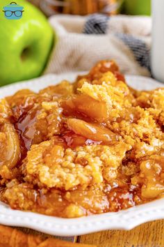 a close up of a plate of food on a table with an apple in the background