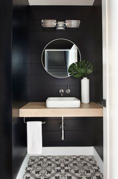 a black and white bathroom with a sink, mirror and toilet paper roll on the counter