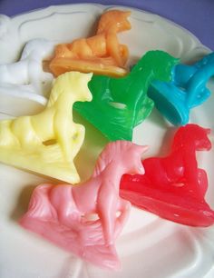 four different colored plastic animals on a white plate