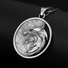 Inspired by a popular TV series, this sterling silver wolf pendant is a captivating accessory for fans and fantasy enthusiasts alike. The iconic emblem represents the fearless monster hunters, drawing on their strength, courage, and determination. With its striking design, this enchanting amulet is the perfect piece for those who appreciate the allure of magic and adventure. Available in four dazzling finishes - oxidized, polished, yellow gold, and rose gold - this unisex necklace offers versati Silver Wolf Design Symbolic Jewelry, Silver Symbolic Wolf Design Jewelry, Viking Style Wolf Design Jewelry Gift, Sterling Silver Wolf Design Jewelry, Symbolic Silver Wolf Design Jewelry, Silver Engraved Jewelry For Costume Events, Silver Wolf Pendant Necklace, Silver Wolf Design Round Pendant Necklace, Collectible Viking Sterling Silver Jewelry