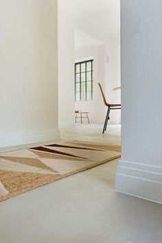 an empty room with a chair and rug on the floor