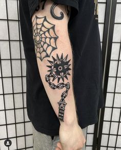 a man's arm with a spider web and key tattoo on the left forearm