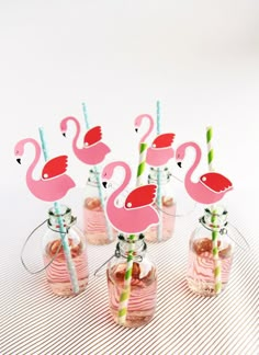 several pink flamingos are in glass vases with straws and drinking straws