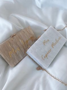 two bags with writing on them laying on a white bed sheet, one has a gold chain and the other has a sign that says mr and mrs