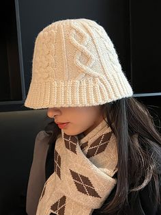 a woman wearing a white knitted hat, scarf and beanie sitting on a bench