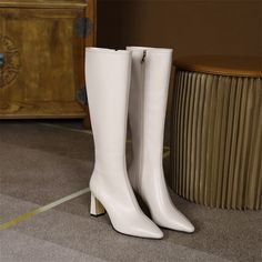 a pair of white high heeled boots sitting on the floor next to a dresser