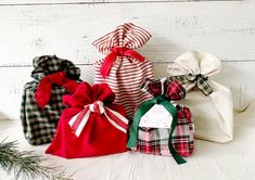 several small bags are lined up next to each other on a white surface, with pine branches in the foreground